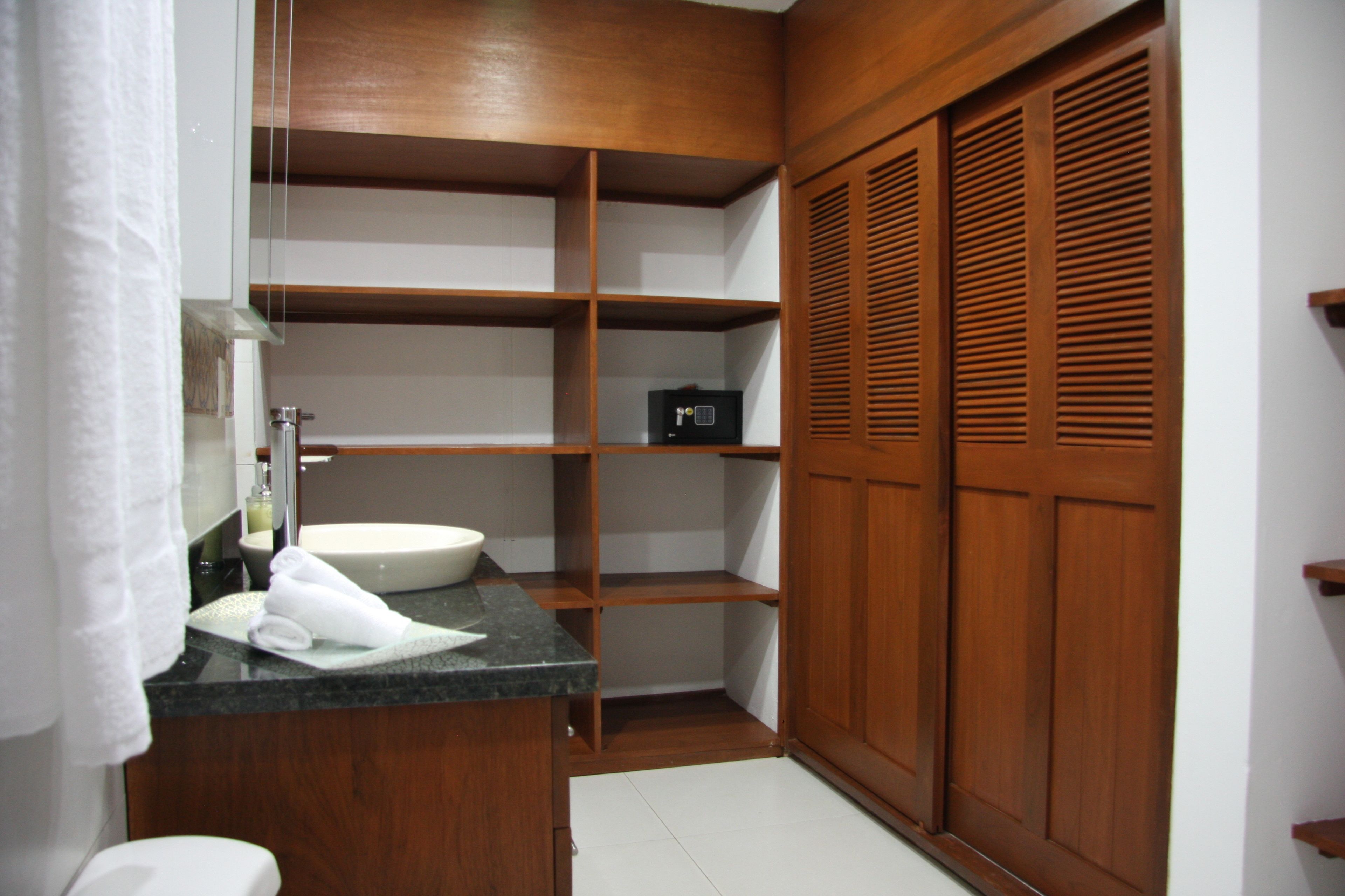 A bathroom with a wooden vanity, a sink, a mirror, and a towel rack.