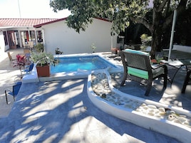 Una piscina al aire libre, sillones reclinables de piscina