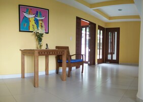 Una habitación amplia con una mesa y sillas de madera, un cuadro enmarcado en la pared y una puerta que da a otra zona.