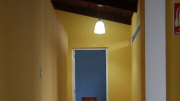 A hallway with yellow walls, a wooden door at the end, and a ceiling light fixture.