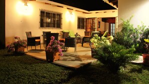 An outdoor patio area with wicker furniture, potted plants, and a well-lit ambiance.
