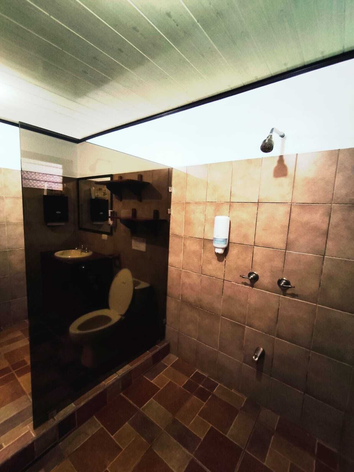 Ein kleines, schlichtes Badezimmer mit Toilette, Waschbecken und Dusche.