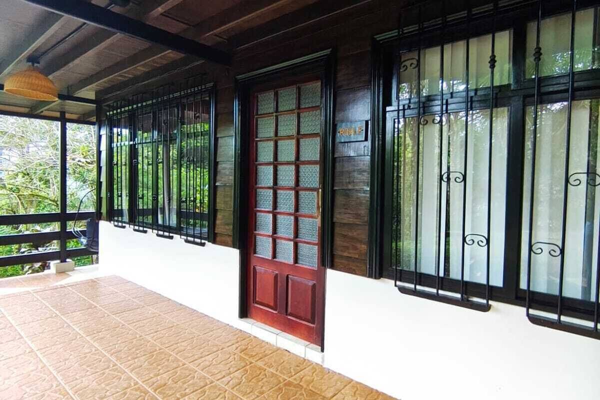 A covered outdoor area with a tiled floor, a wooden ceiling, and a red door with glass panels.