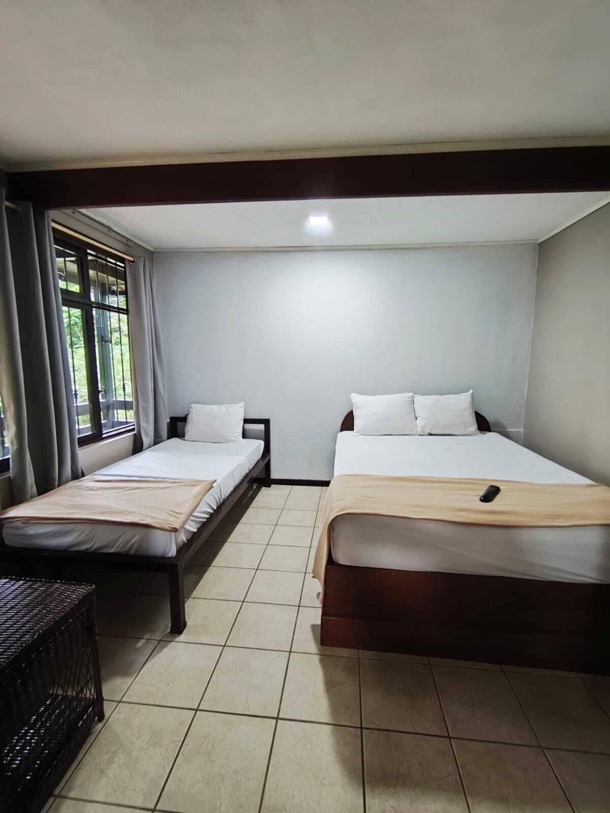 Una habitación con dos camas individuales, una mesita y una ventana con cortinas.