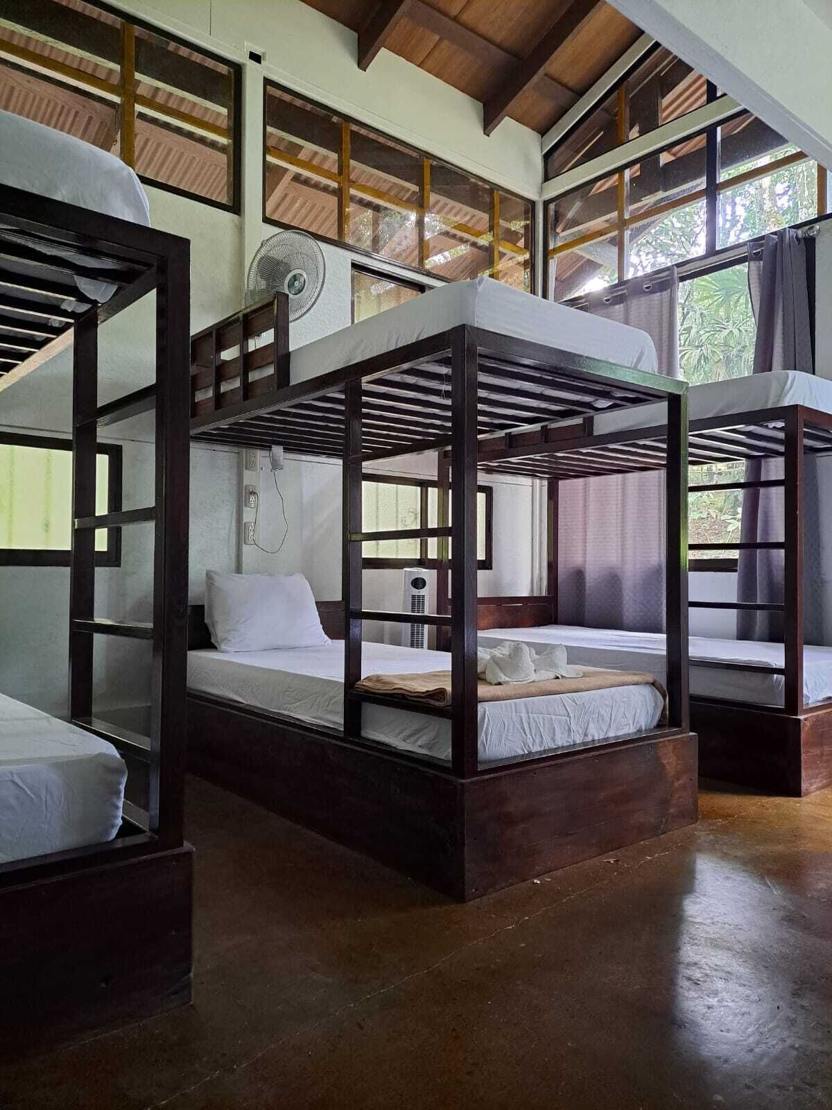 Ein Zimmer mit Etagenbetten, Deckenventilator und großen Fenstern.