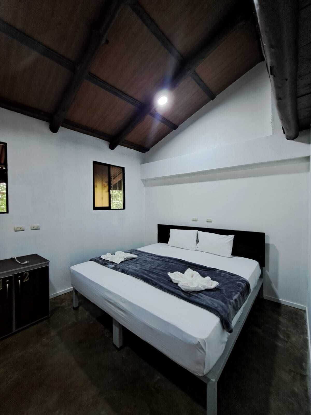 A hotel room with a single bed, a small desk, and a window.