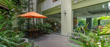Un patio interior con plantas en macetas, suelo de ladrillo y puerta de cristal.