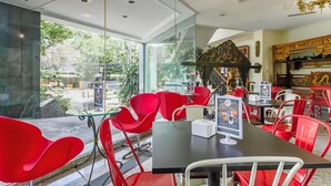 Un café moderno con sillas rojas, un muro de cristal y vista a la calle.