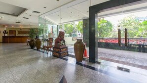 Un vestíbulo amplio con una recepción, jarrones decorativos y una estatua.