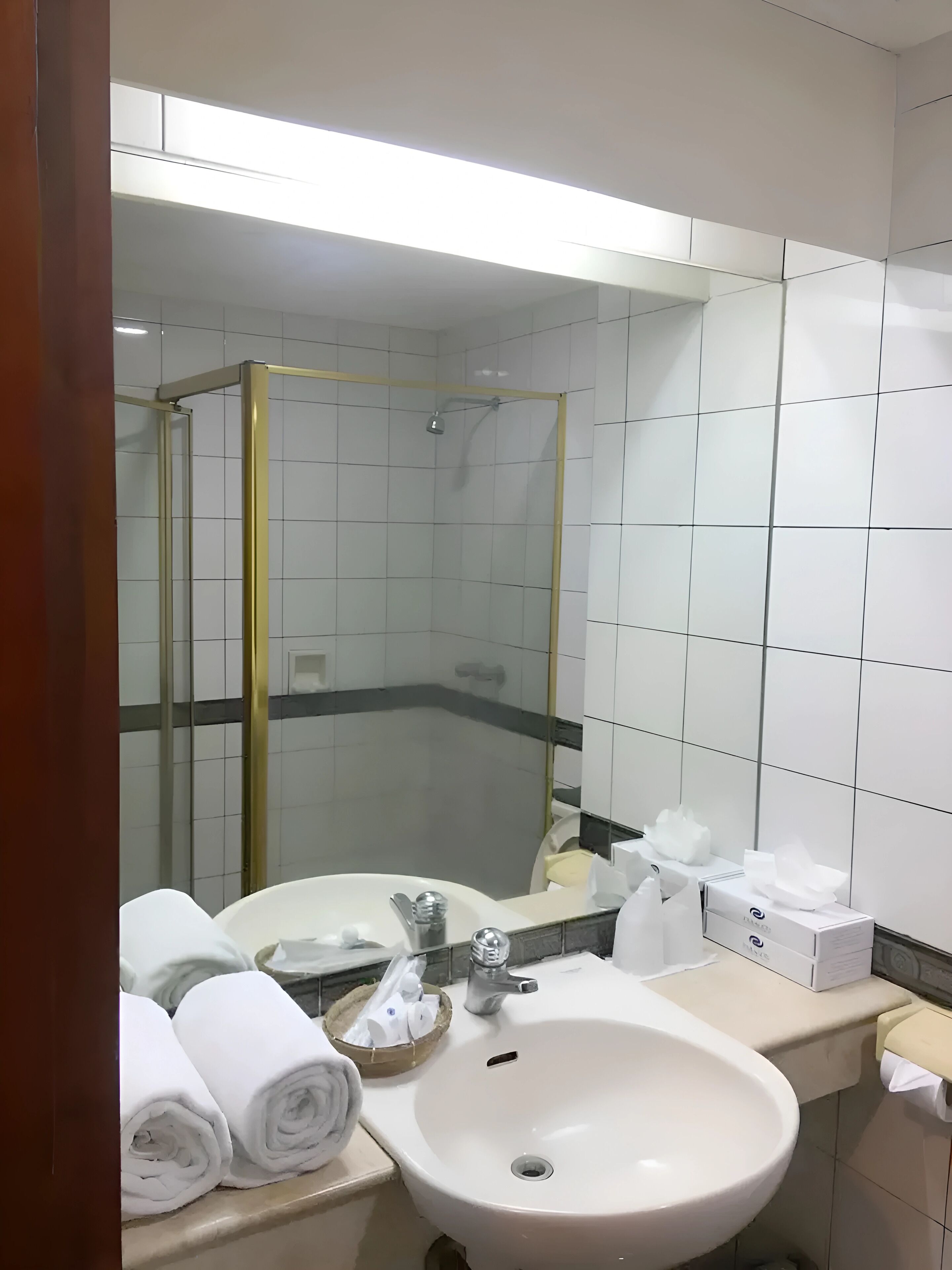 A bathroom with a white sink, mirror, and shower enclosure.
