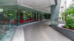 Un moderno vestíbulo de hotel con paredes de vidrio, asientos rojos y un patrón de suelo en espiga.