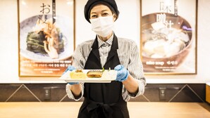 Una persona con uniforme sosteniendo una bandeja con comida.