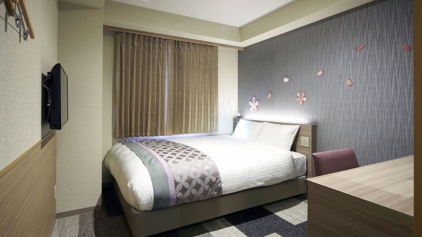 Une chambre d’hôtel avec un lit, un bureau, une télévision et une fenêtre avec des rideaux.