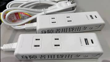 Three white power adapters with Japanese text and a cable.