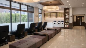 Un moderno espacio de spa con sillones de masaje, un mostrador de recepción y vistas a zonas verdes.