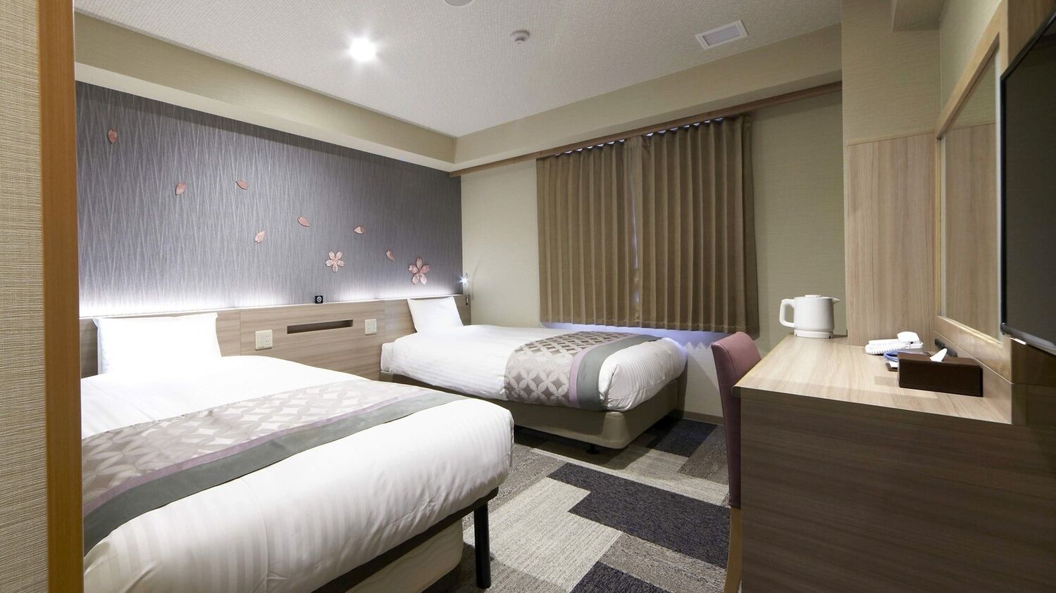 Une chambre d’hôtel avec deux lits, un bureau, une télévision et une fenêtre avec des rideaux.