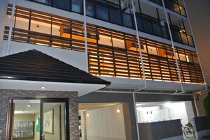 Un edificio moderno con estructura de dos pisos, ventanas amplias y un área de acceso cubierta.