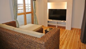 A cozy room with a bed, a TV, and a window with curtains.