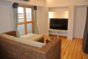 Una habitación acogedora con una cama, un televisor y un ventanal con cortinas.
