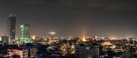 A nighttime cityscape with illuminated buildings and a prominent skyscraper.