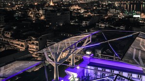 A modern building with a glass facade and a purple-lit interior. - Point Boutique Hotel (Phnom Penh)