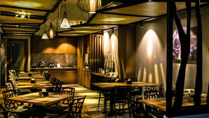 A restaurant with multiple dining tables and chairs, a kitchen area, and pendant lighting. - Point Boutique Hotel (Phnom Penh)