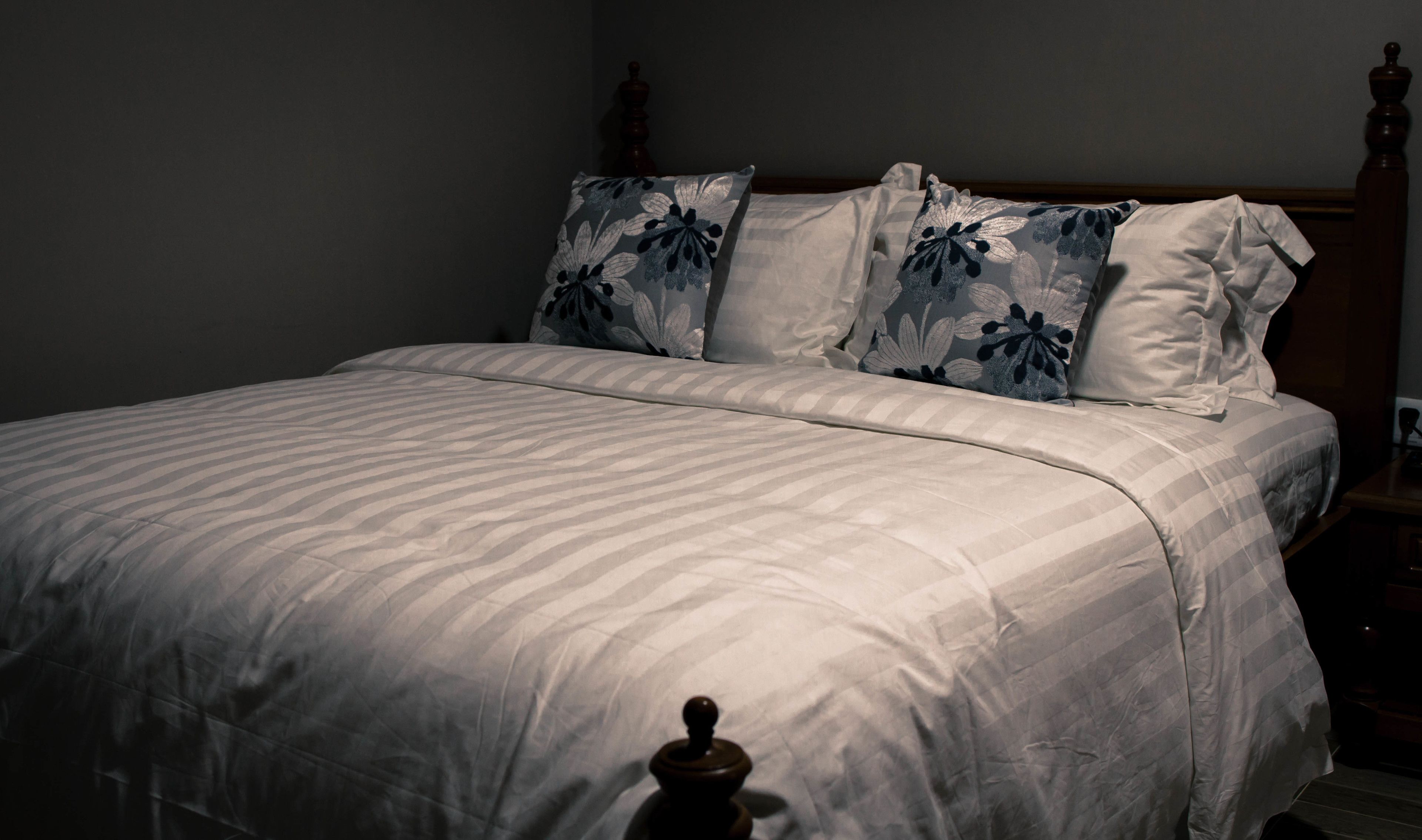 A neatly made bed with a striped bedspread and two floral pillows.