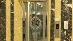 Un ascensor con puerta de cristal y un emblema decorativo.