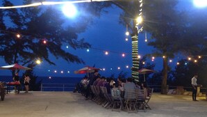 Un espacio al aire libre con mesas y sillas dispuestas bajo luces colgantes.