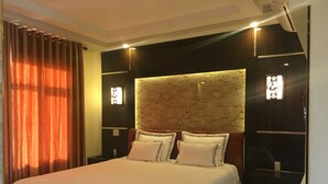 Una cama bien hecha con sábanas blancas, cabecera con diseño texturizado y dos mesitas de noche con lámparas.