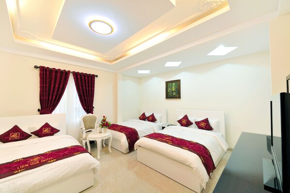 A hotel room with two beds, a desk, a chair, a TV, and a ceiling light. - Phuoc Son Hotel (Xuan Huong - Da Lat)