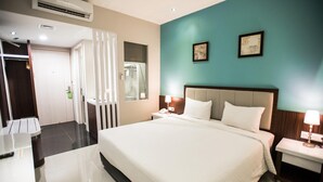 Une chambre d’hôtel avec un grand lit, des tables de chevet, un miroir et une porte donnant sur une salle de bain.