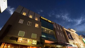 Un hôtel appelé « Happy Inn » avec une enseigne indiquant qu’il est ouvert 24 heures sur 24.
