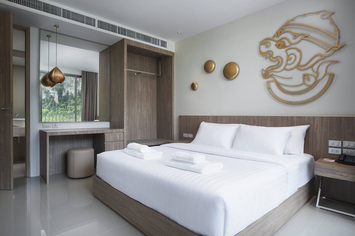 A modern hotel room with a large bed, a wooden desk, and a bathroom.