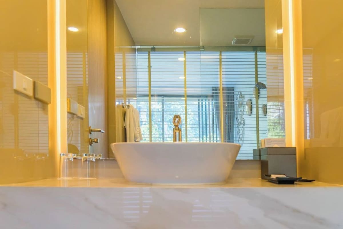 A modern bathroom with a freestanding bathtub, a glass shower enclosure, and a view of the outdoors through large windows.