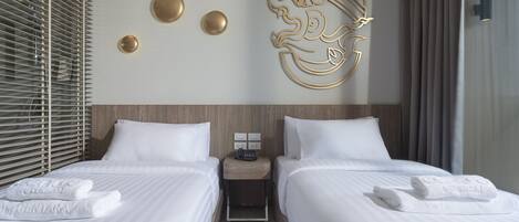 A hotel room with two beds, a wooden headboard, a wall-mounted light fixture, and a decorative wall piece.