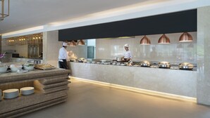 A modern kitchen with a buffet setup, including a counter with food items and a chef preparing food. - Centara Life Phu Pano Krabi (Krabi)