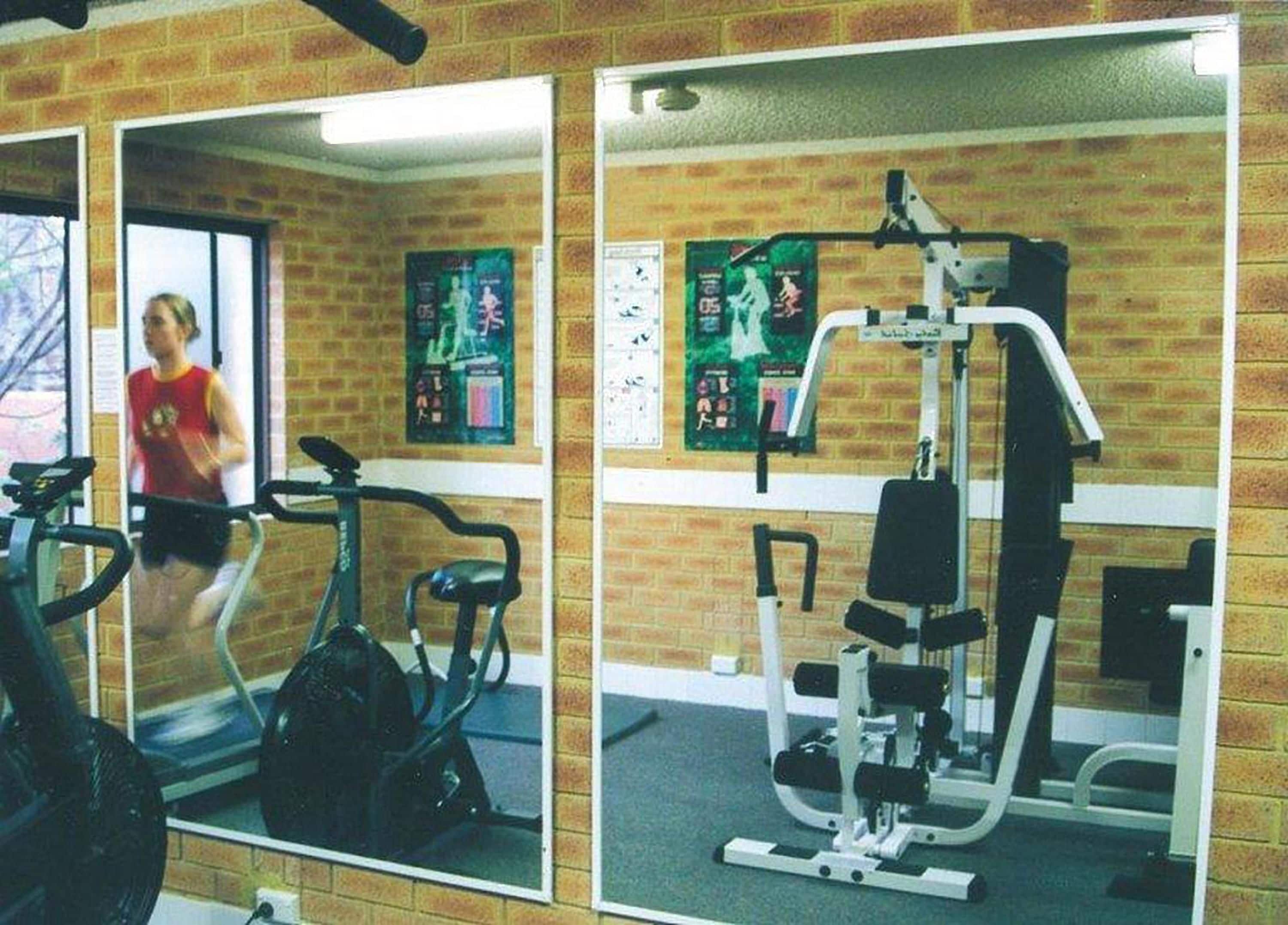 A gym with exercise equipment, a mirror, and motivational posters on the wall.