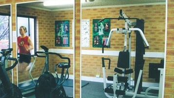 A gym with exercise equipment, a mirror, and motivational posters on the wall.