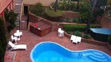 Una piscina con sillones de descanso y una pequeña zona de terraza.