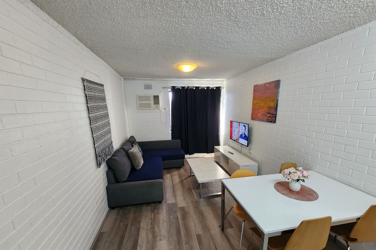 Ein modernes Wohnzimmer mit einer Couch, einem Esstisch und einem Fernseher.