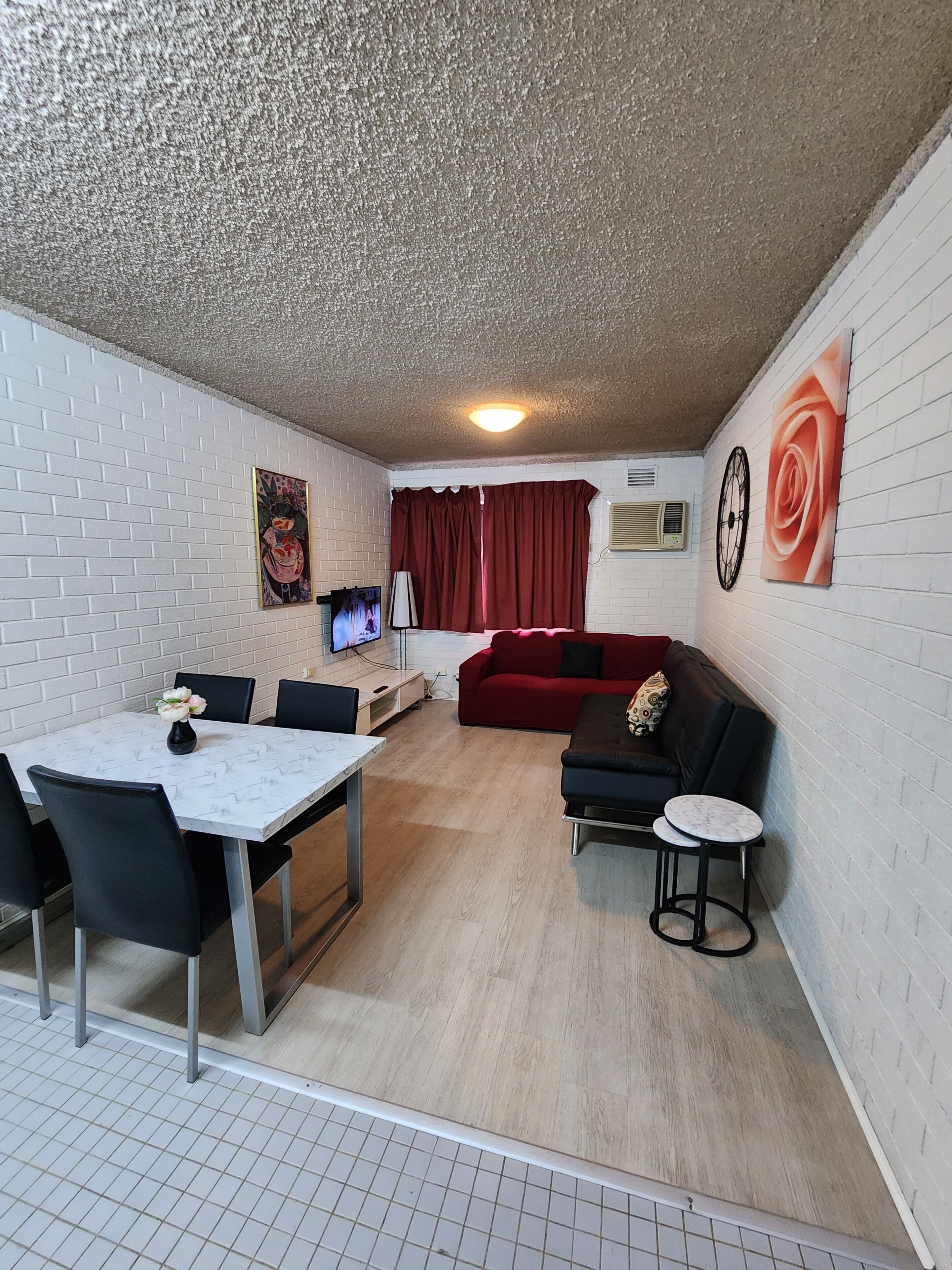A compact living space with a dining area, a sofa, a TV, and artwork on the walls.