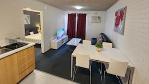 A compact hotel room with a kitchenette, a bed, a TV, a dining area, and a bathroom. - Perth City Apartment Hotel (West Perth)