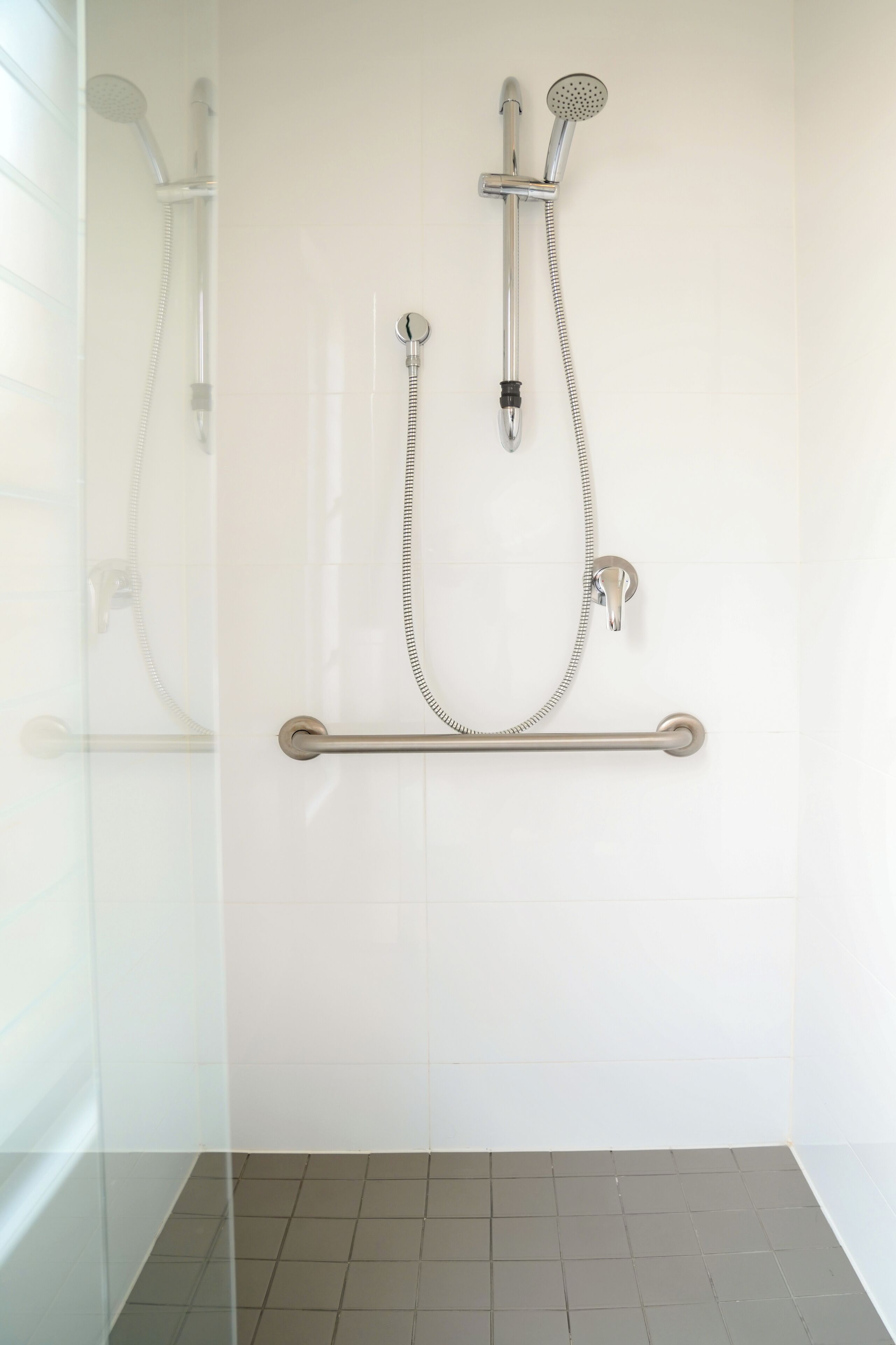 A modern bathroom with a glass shower enclosure, a handheld showerhead, and a wall-mounted faucet.