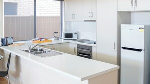 Een moderne keuken met een centraal eiland, roestvrijstalen apparatuur en een raam voor natuurlijk licht.