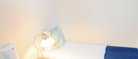 Une chambre d’hôtel avec deux lits simples, une table de chevet avec une lampe et un tableau au mur.