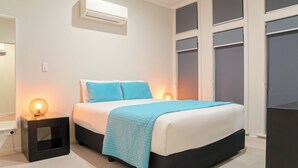 Een slaapkamer met een bed, nachtlampjes, een airconditioning en een kledingkast.