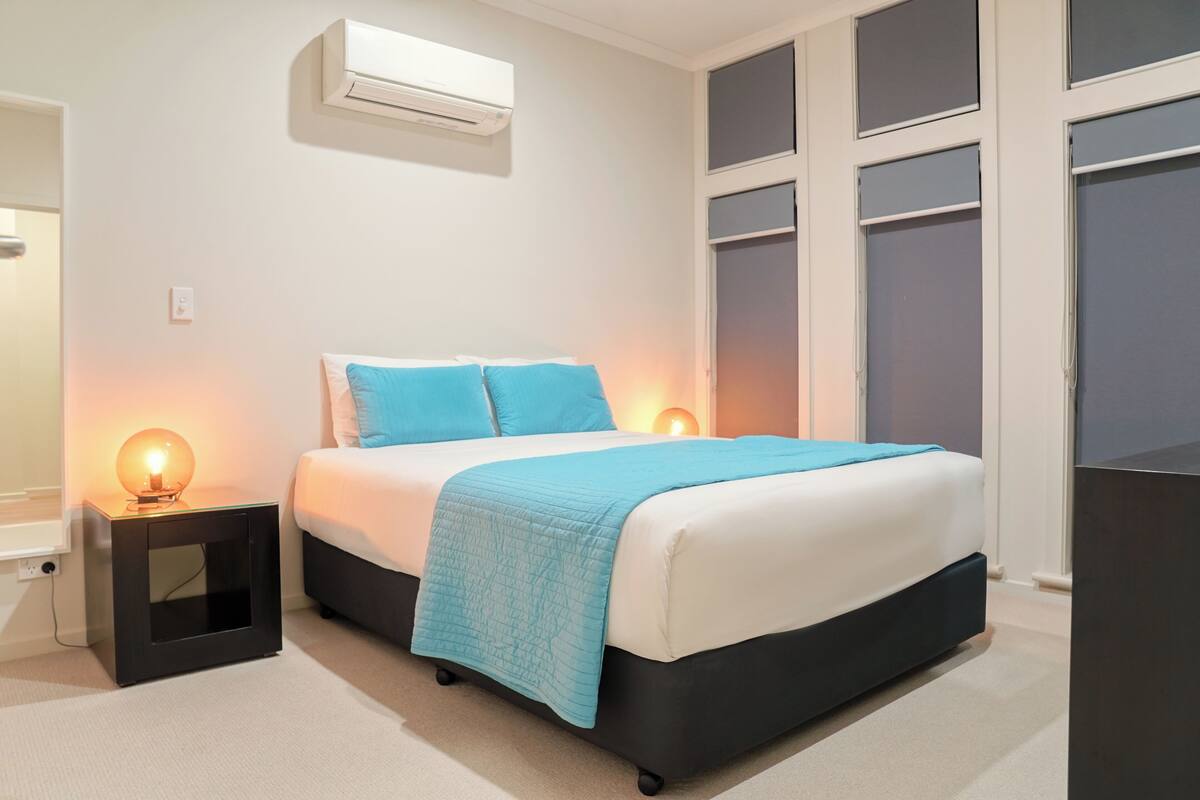 Een slaapkamer met een bed, nachtlampjes, een airconditioning en een kledingkast.