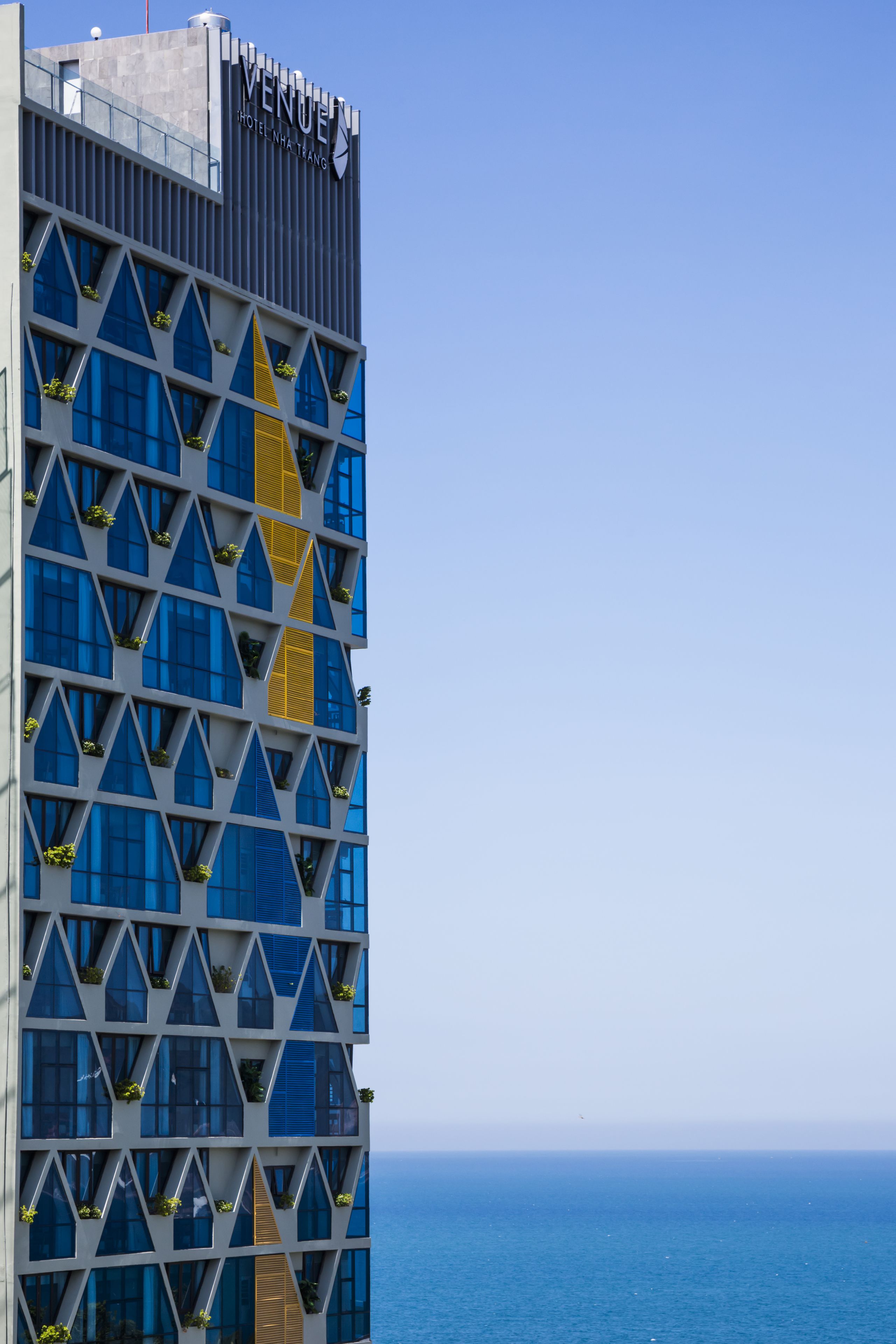 Un hotel moderno con una fachada geométrica, ventanas amplias y una vista despejada del mar.