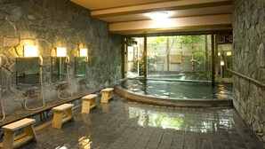A stone-walled indoor pool area with benches and lighting fixtures. - Yufuin Santokan (Yufu)